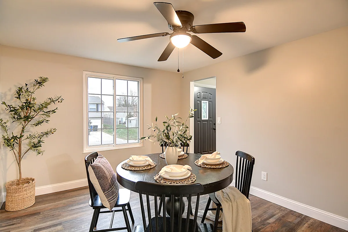 Renovated Huber Heights dining room after EZ Sell Homebuyers — open walls, modern dining set, ceiling fan, luxury vinyl plank, view to front yard