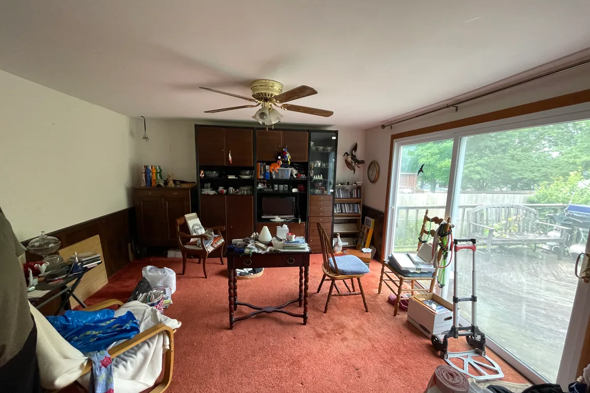Huber Heights Chukar Drive back family room before sale — wood-paneled wainscot, red carpet, cluttered furniture, dated entertainment wall