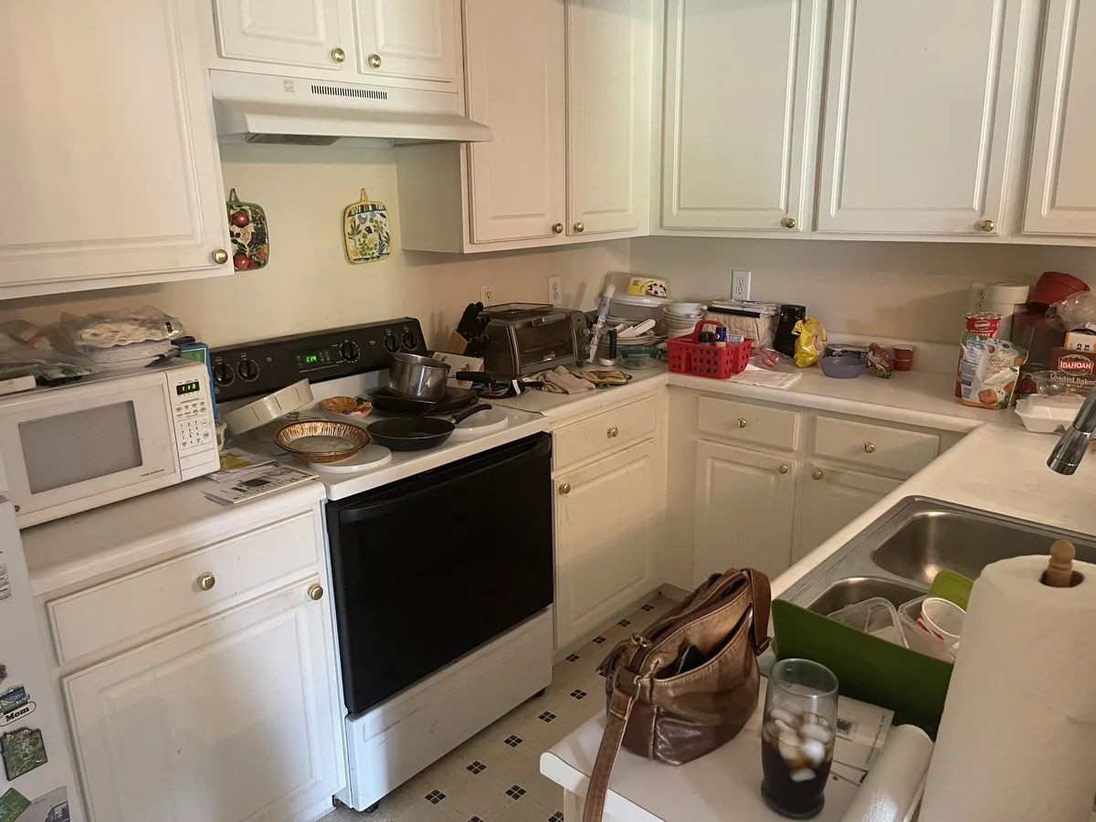 Miamisburg 1539 Commons Drive kitchen before EZ Sell Homebuyers cash purchase — dated white cabinets, laminate counters, brass hardware, counter clutter, white appliances