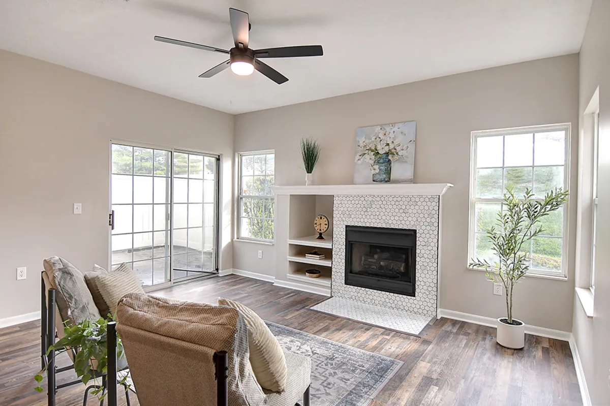 Renovated Miamisburg 1539 Commons Drive living room after EZ Sell Homebuyers — luxury vinyl plank floors, fresh greige paint, hex-tile fireplace surround, modern ceiling fan, bright natural light