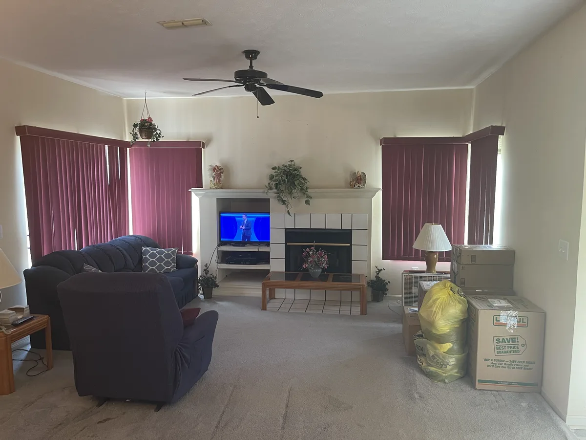 Miamisburg 1539 Commons Drive living room before cash sale to EZ Sell Homebuyers — burgundy vertical blinds, tile fireplace surround, beige carpet, dated ceiling fan