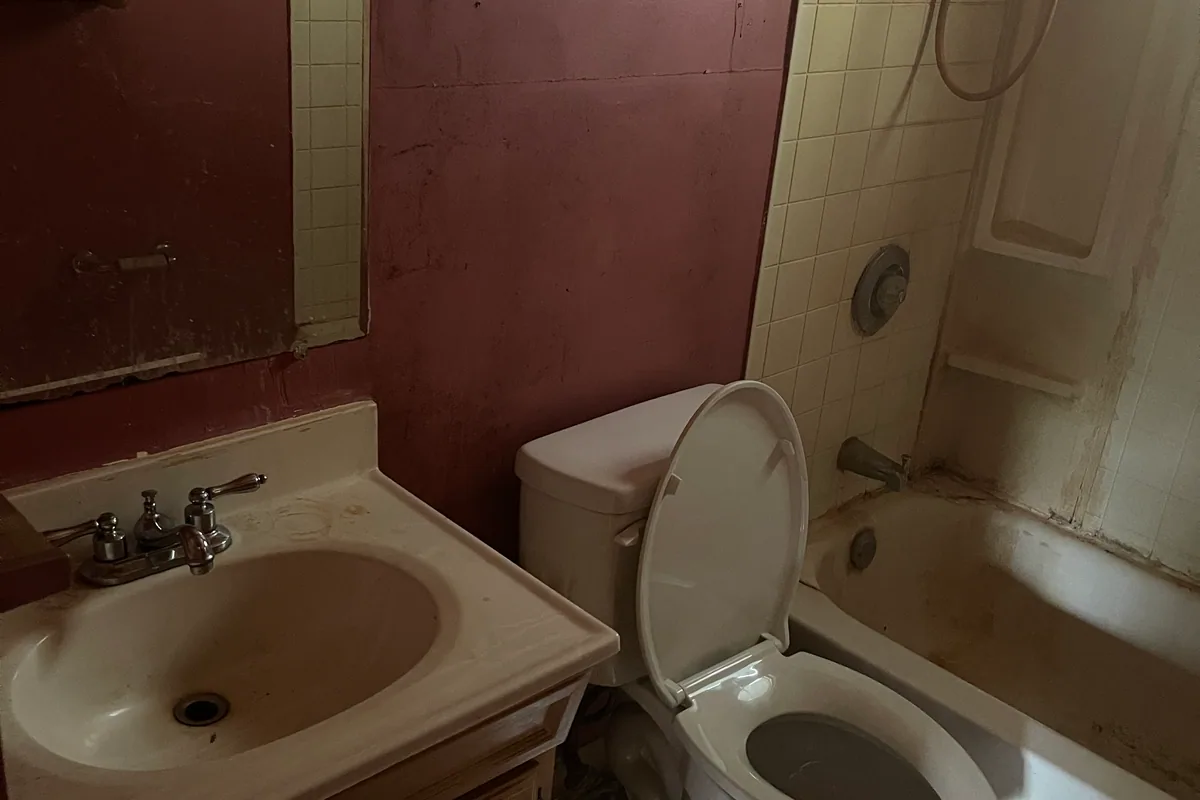 Fairborn Florence Avenue bathroom before EZ Sell Homebuyers — pink walls, stained vanity, warped mirror, mildewed tub surround