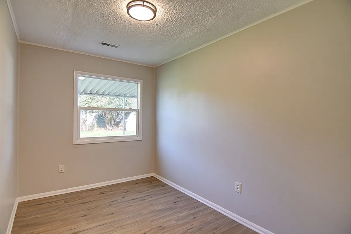Renovated Fairborn bedroom after EZ Sell Homebuyers — fresh neutral greige paint, new luxury vinyl plank flooring, modern flush-mount light fixture