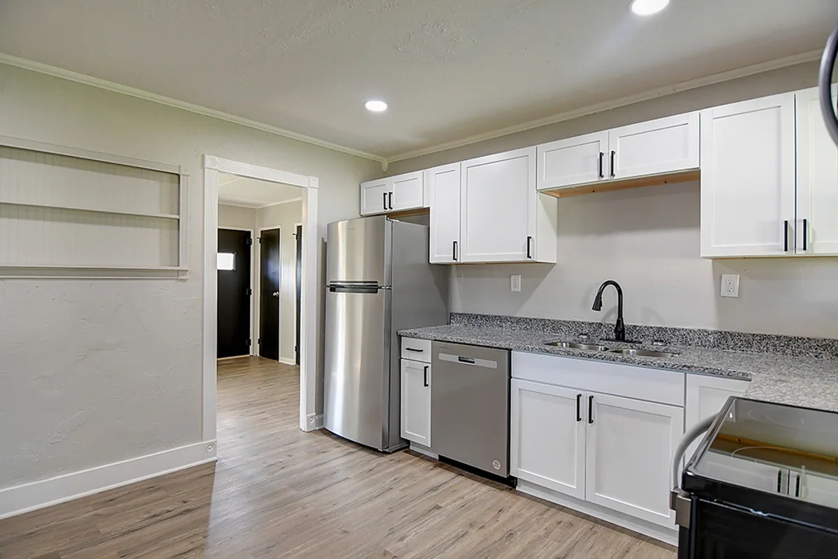 Renovated Fairborn dining nook after EZ Sell Homebuyers — built-ins removed, smooth painted wall, open sightline into new white kitchen, luxury vinyl plank