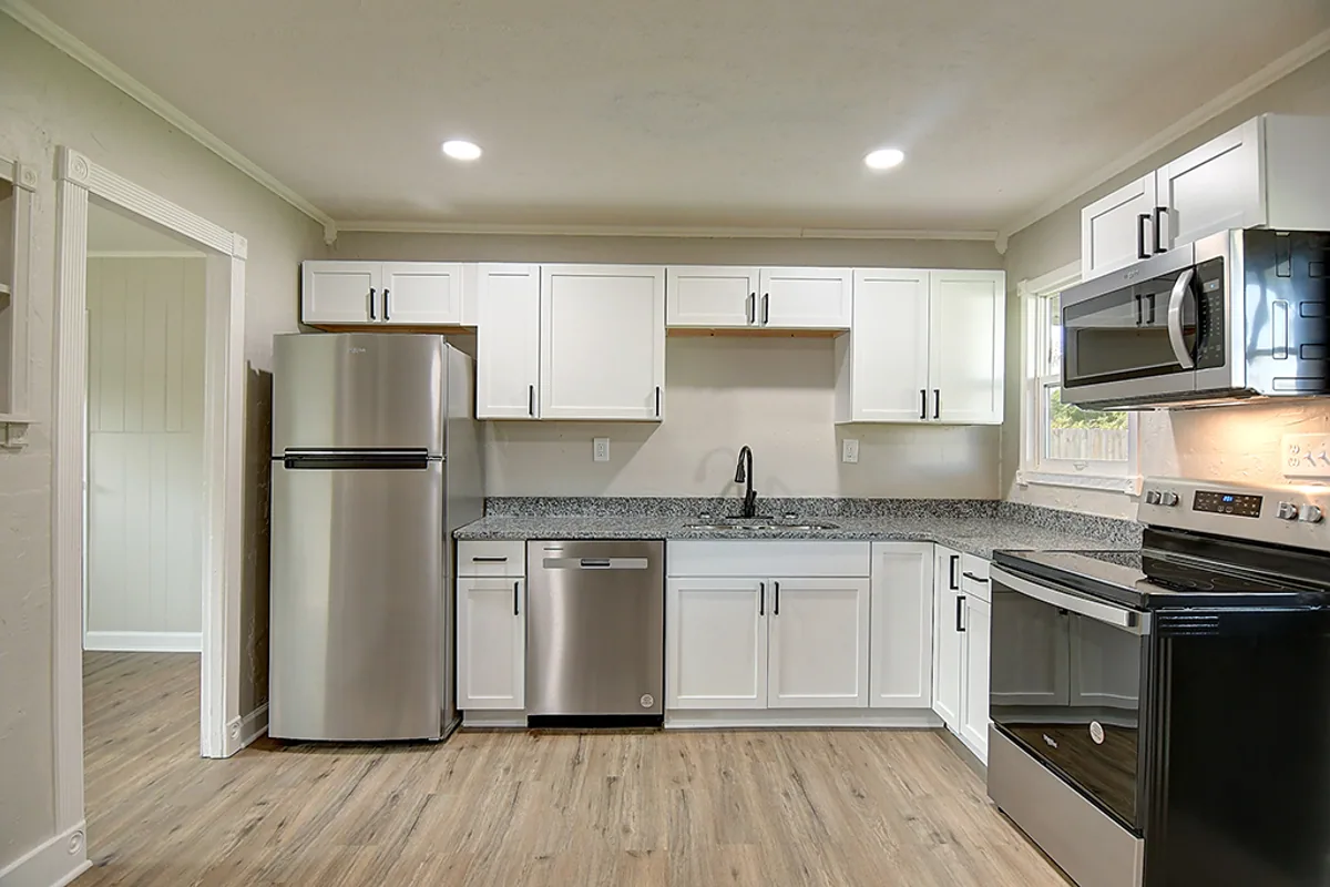 Renovated Fairborn kitchen after EZ Sell Homebuyers — white shaker cabinets, granite countertops, stainless steel appliances, modern black faucet