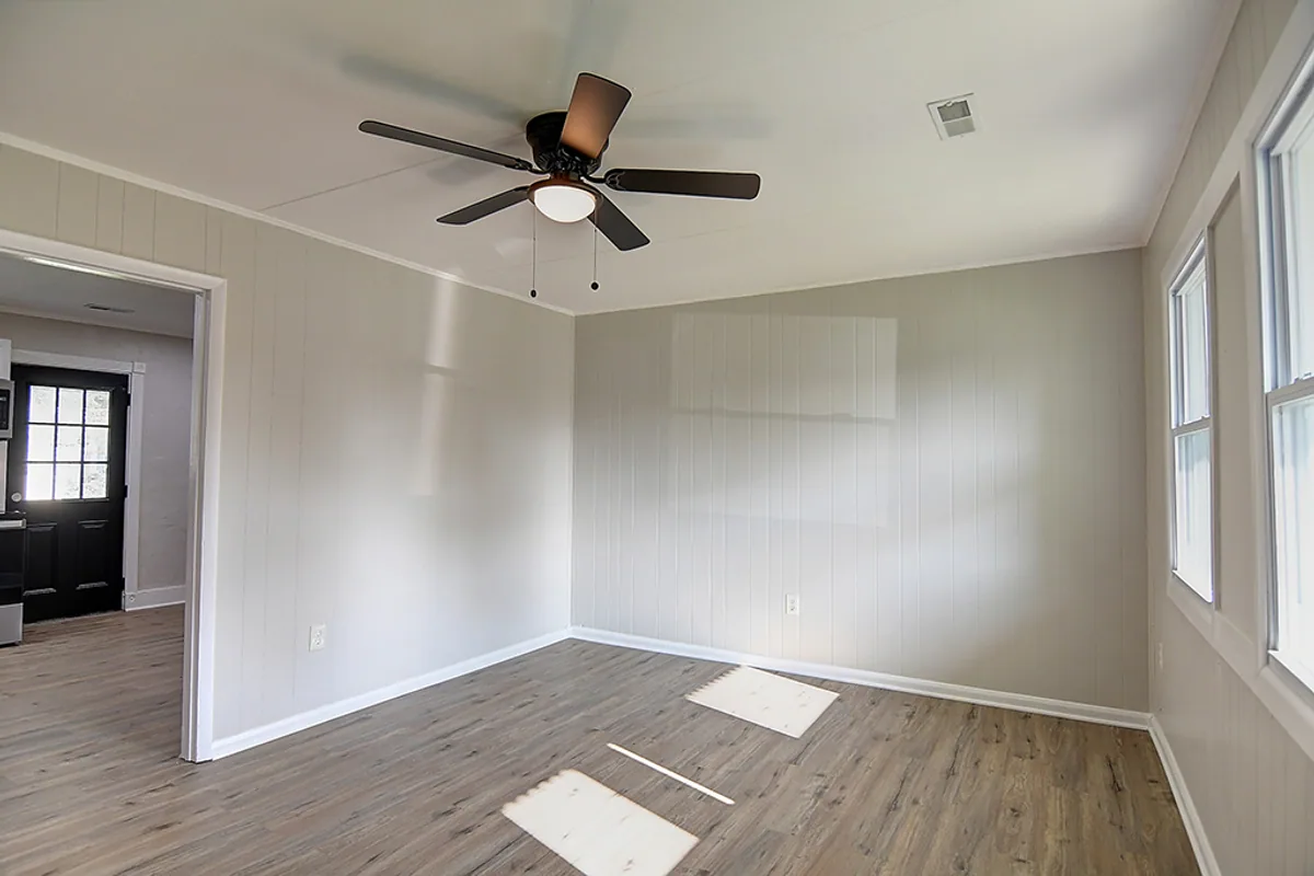 Renovated Fairborn living room after EZ Sell Homebuyers — clean gray painted walls, new luxury vinyl plank floors, modern ceiling fan, fresh crown molding