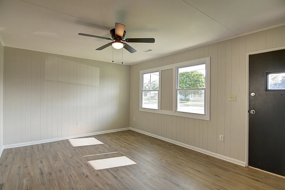 Renovated Fairborn picture window wall after EZ Sell Homebuyers — bright natural light, fresh wall paint, modern black entry door, new luxury vinyl plank