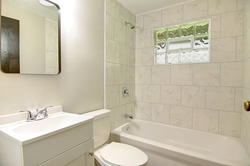 Renovated Kettering bathroom — new tiled tub surround, glass block window, clean white vanity, modern fixtures