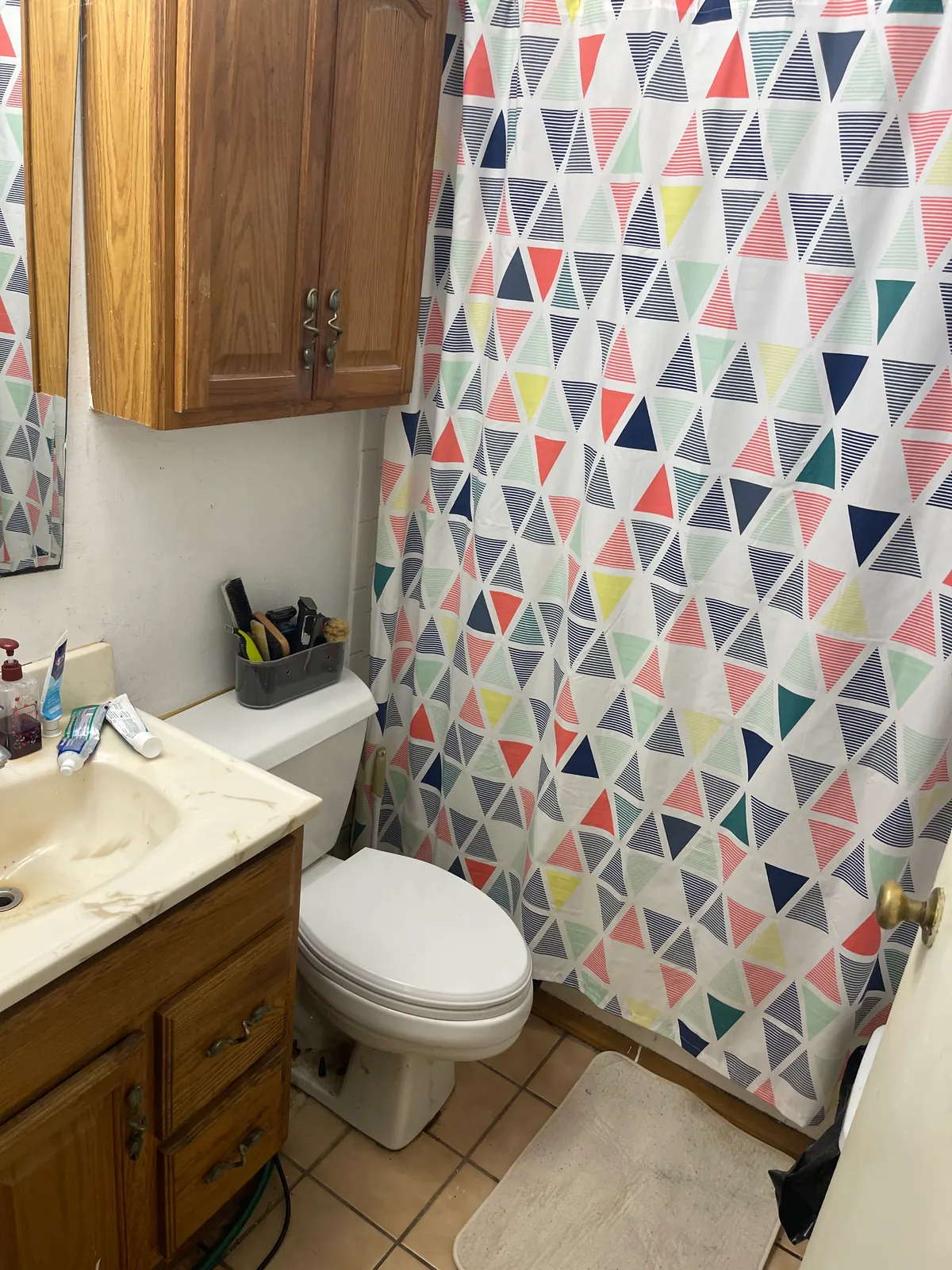 Kettering ranch bathroom before sale — stained marbled vanity, dated shower curtain, original fixtures