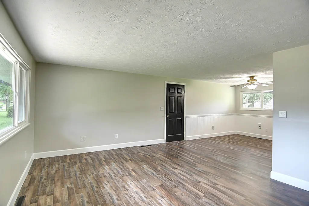 Same Kettering great room after renovation — open plan, fresh neutral paint, new flooring, ceiling fan