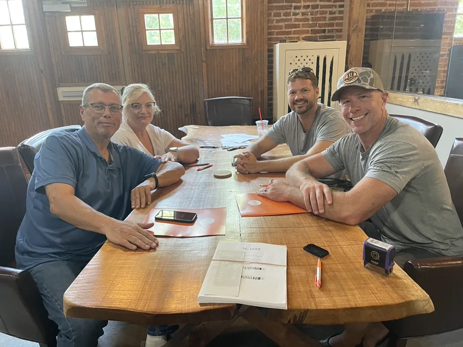 Family smiling at closing table after selling their Dayton home for cash